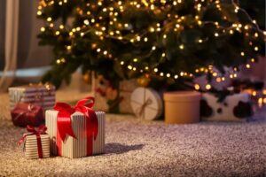 Christmas gifts in boxes sitting under a fir tree.