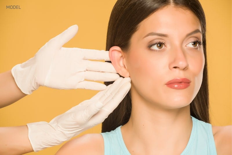 Doctor touching a woman's ear that they are about to pin back.