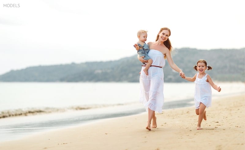 Mother walking along the beach with her children.