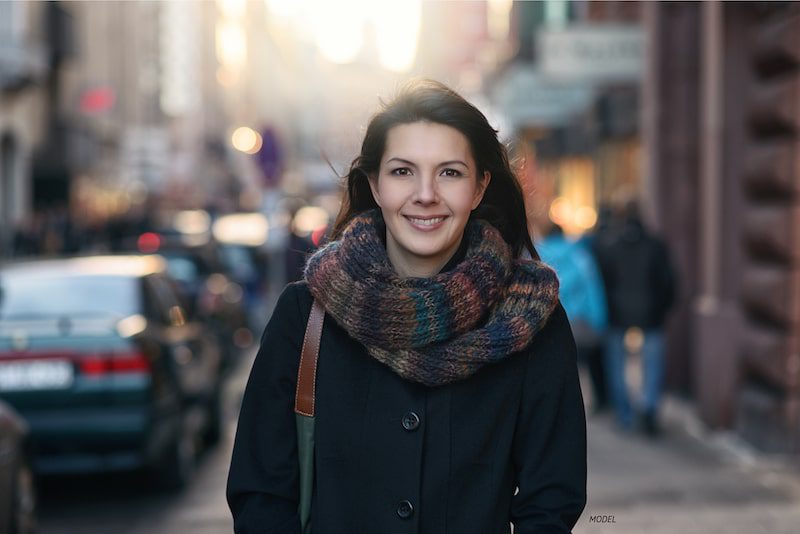 Woman standing on a city street, wrapped in jacket and scarf