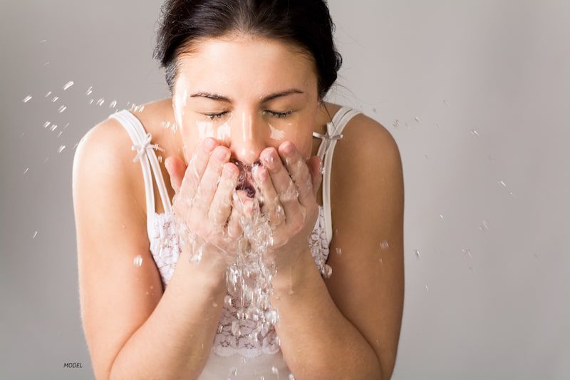 Woman splashing water on her face.