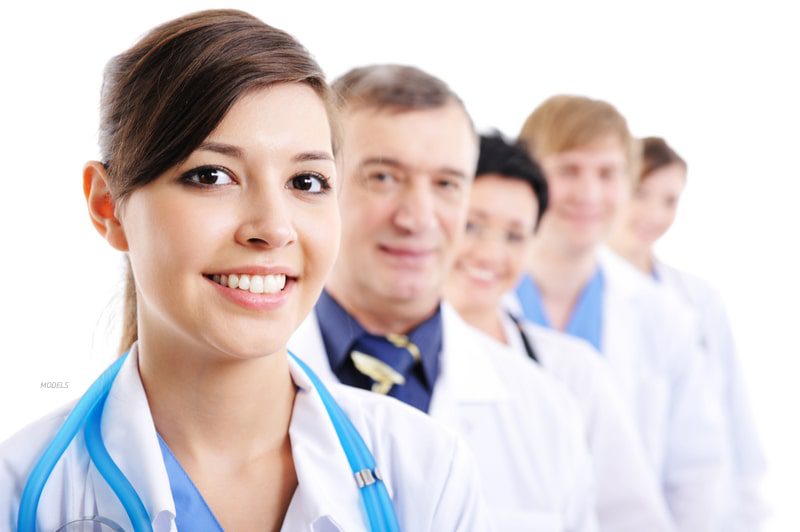 A line-up of different doctors looking directly at the camera and smiling