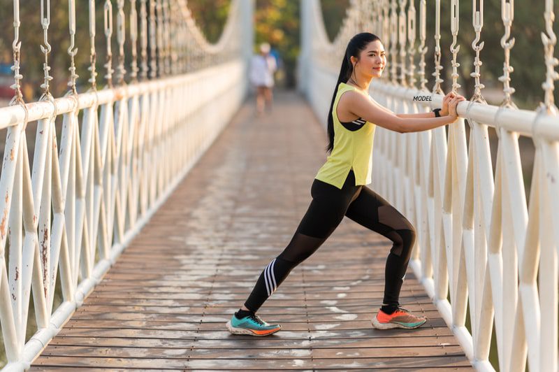 Woman stretching on a bridge before going on a run.