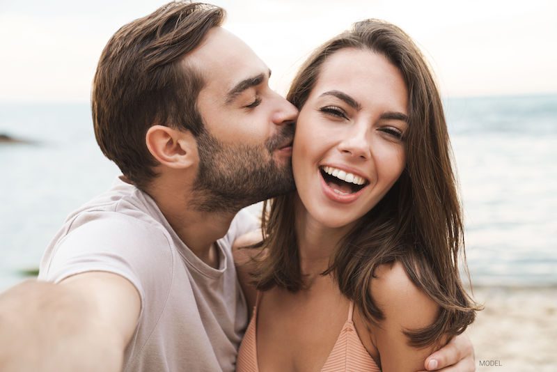 Young and attractive couple smiling and hugging while taking a selfie.