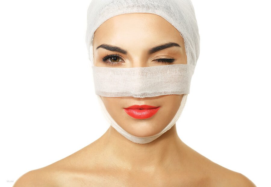 Woman with bandages over her head and nose 